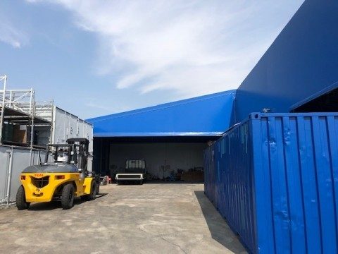 フォークリフトと青いコンテナが置かれたコンテナの加工場所