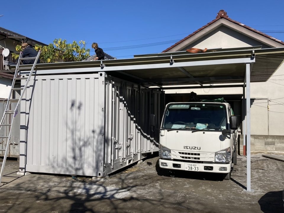 2台のコンテナの間に屋根を架け、下にトラックを停めた様子