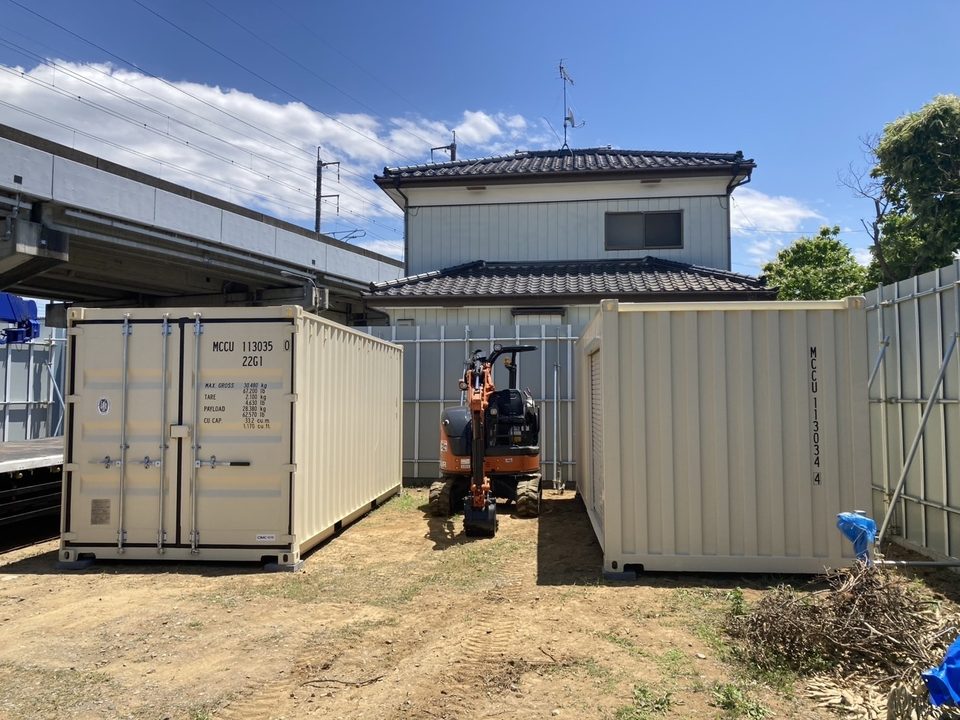 住宅の敷地にベージュのコンテナ2台を据え付けている様子